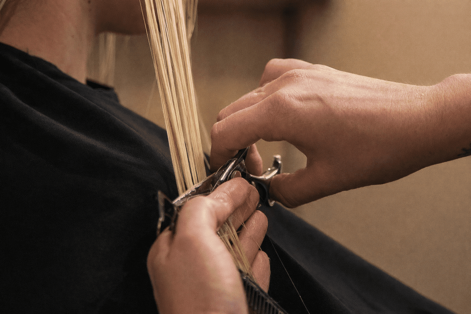 Hair being trimmed with scissors in a salon setting.
