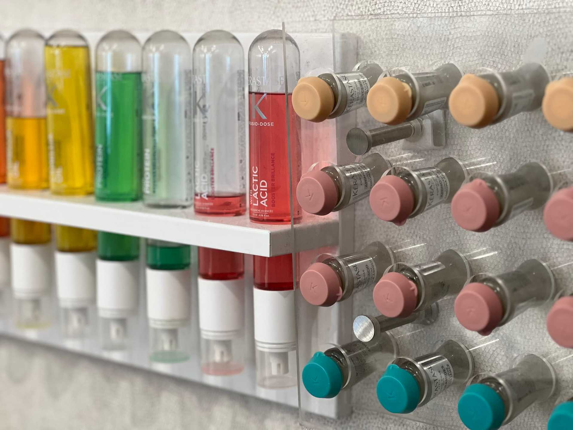 Test tubes and vials with colorful liquids displayed on a wall shelf.